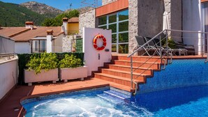 A swimming pool with a lifebuoy, steps leading to a building, and a mountainous backdrop. - Entregredos: Rural House in Sierra de Gredos with Pool and Jacuzzi (Guisando)