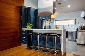 A modern kitchen with a built-in refrigerator, bar stools, and a window.