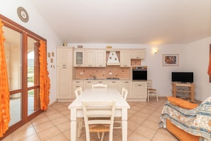 Cocina compacta con una mesa de comedor, sillas, televisor y sofá.