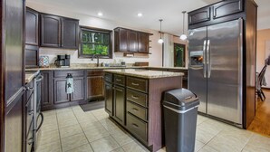 Cozinha moderna com armários de madeira escura, geladeira de aço inoxidável e piso cerâmico.
