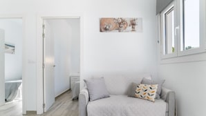 A modern living room with a grey sofa, a small table, and a painting on the wall.
