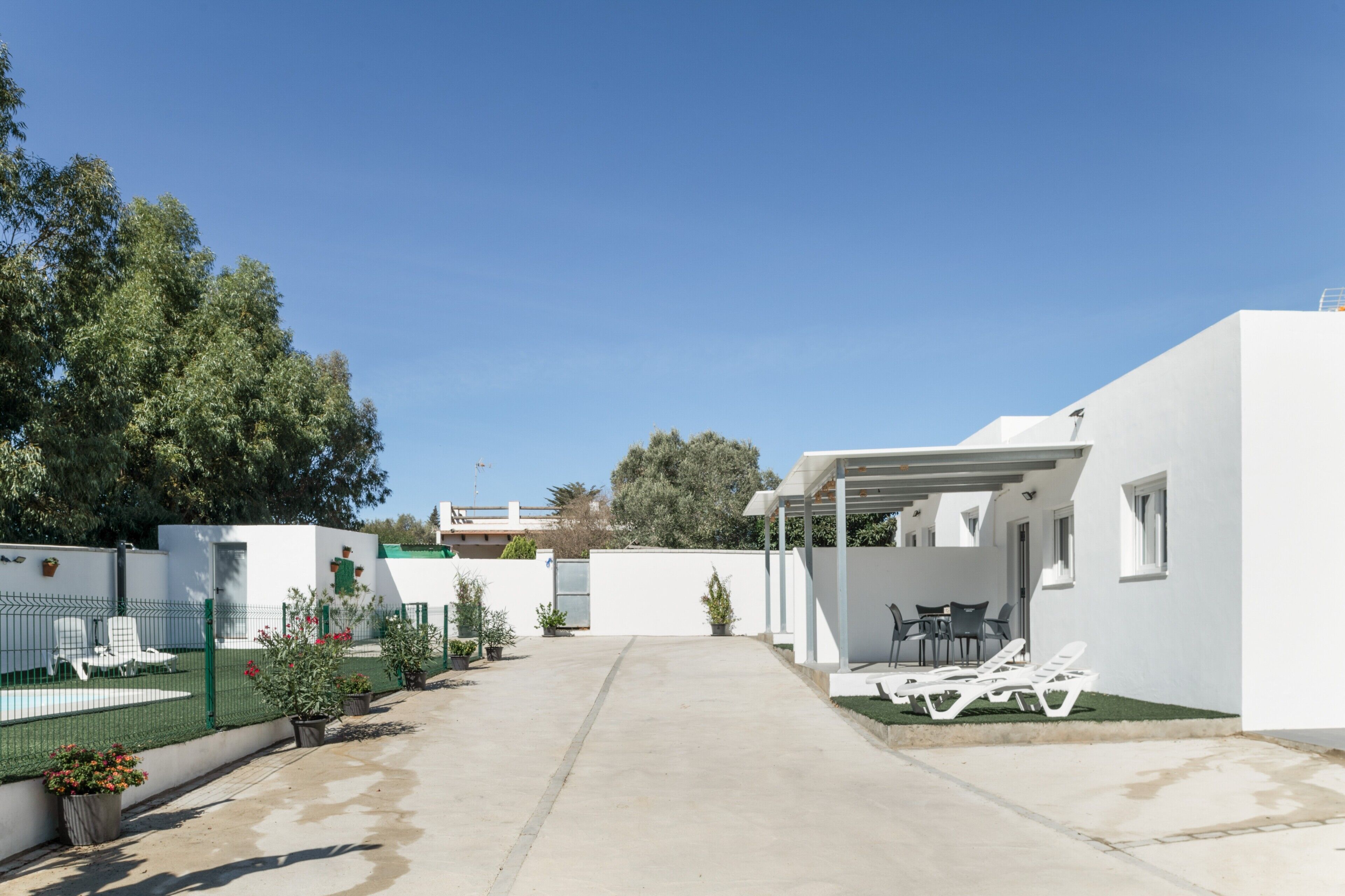 Un patio moderno al aire libre con piscina, sillas de descanso y una zona de estar cubierta.