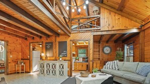 A cozy cabin interior with a wooden interior, a kitchen area, and a seating area with a sofa and a table.