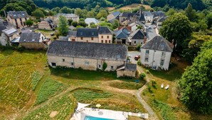 An aerial view of a village with traditional stone buildings, a swimming pool, and a vineyard.
