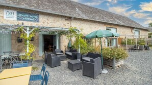 A rustic stone building with outdoor seating and a sign for 'EPICERIE BISTRO CAMPING.'