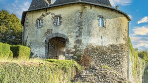 A historic stone building with a round tower, arched entrance, and multiple windows.