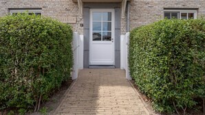 A brick building with a white door and a sign reading "CARFLEUR 13".