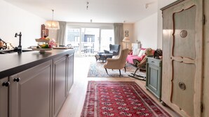 A spacious living area with a large window, a red patterned rug, and a cozy seating arrangement.