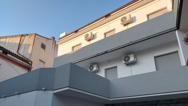 A modern building with a flat roof, multiple air conditioning units, and a large garage door.