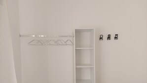 A white closet with open shelves and a hanging rod.