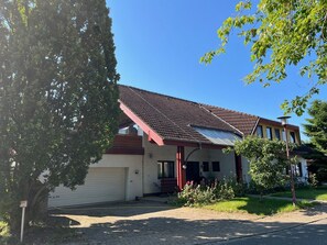 Une maison de plain-pied avec un toit rouge, un garage et un petit porche.