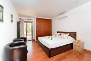 Une chambre à coucher avec un lit en bois, une table de chevet avec une lampe, une chaise et une porte donnant sur un balcon.