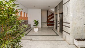 Un interior moderno con piso de mármol, una escalera y una planta en maceta.