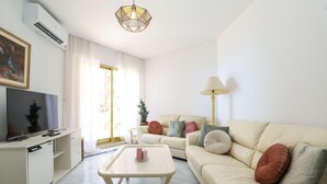 Una sala de estar con sofá, mesa de centro, televisor y lámpara.