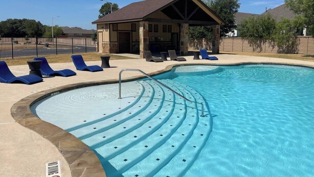 A swimming pool with a built-in slide, lounge chairs, and a covered seating area.