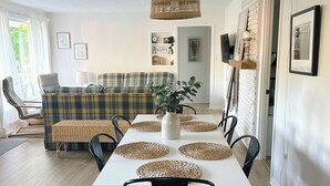 Un'area pranzo con un tavolo bianco, sedie nere e sottopiatti in tessuto.