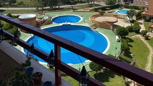 A balcony with a view of a coastal area, including a marina and a large swimming pool complex. - WELCS ESTUDIO 172 EMP con piscina comunitaria (Rosas / Roses)