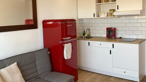 A compact kitchen with white cabinets, a red refrigerator, and a grey sofa. - WELCS ESTUDIO 172 EMP con piscina comunitaria (Rosas / Roses)