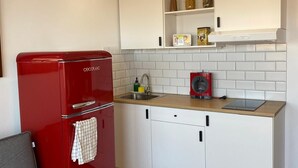 A compact kitchen with white cabinets, a red refrigerator, and a grey sofa. - WELCS ESTUDIO 172 EMP con piscina comunitaria (Rosas / Roses)