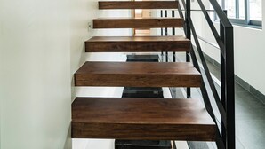 A modern staircase with wooden steps and black railings, leading to an upper floor. - Hajime Homestay (Hue)