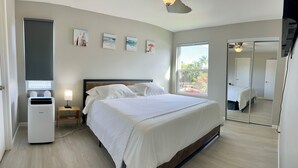 A bedroom with a bed, a heater, a nightstand, a mirror, and artwork on the wall. - Cozy 2-bedroom condo with WiFi, AC in-both bedrooms - Waikoloa Village (Waikoloa Village)