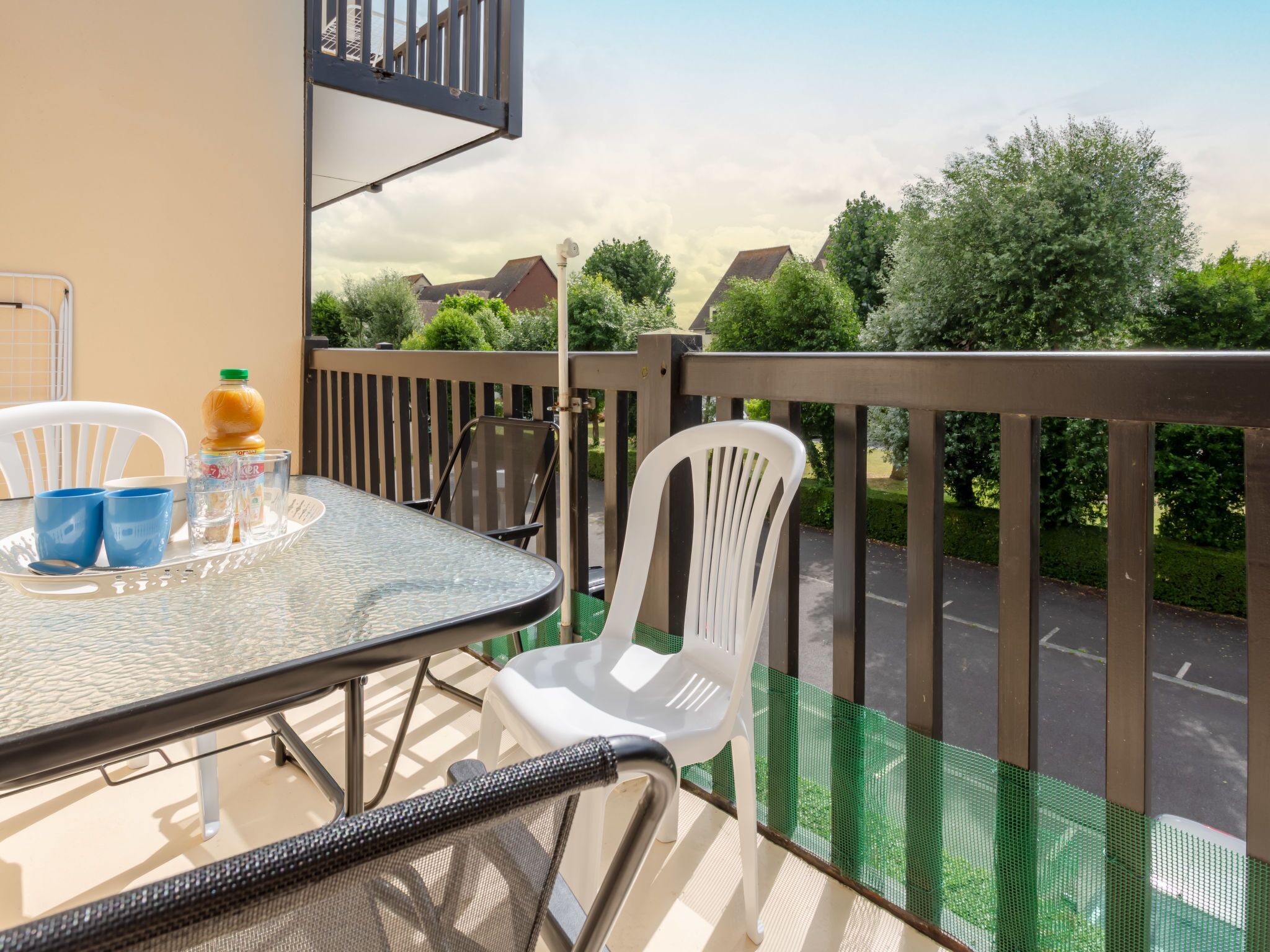 A balcony with a table, chairs, and a bottle of orange juice.