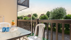 A balcony with a table, chairs, and a bottle of orange juice. - Fleur Marine by Interhome (Cabourg)