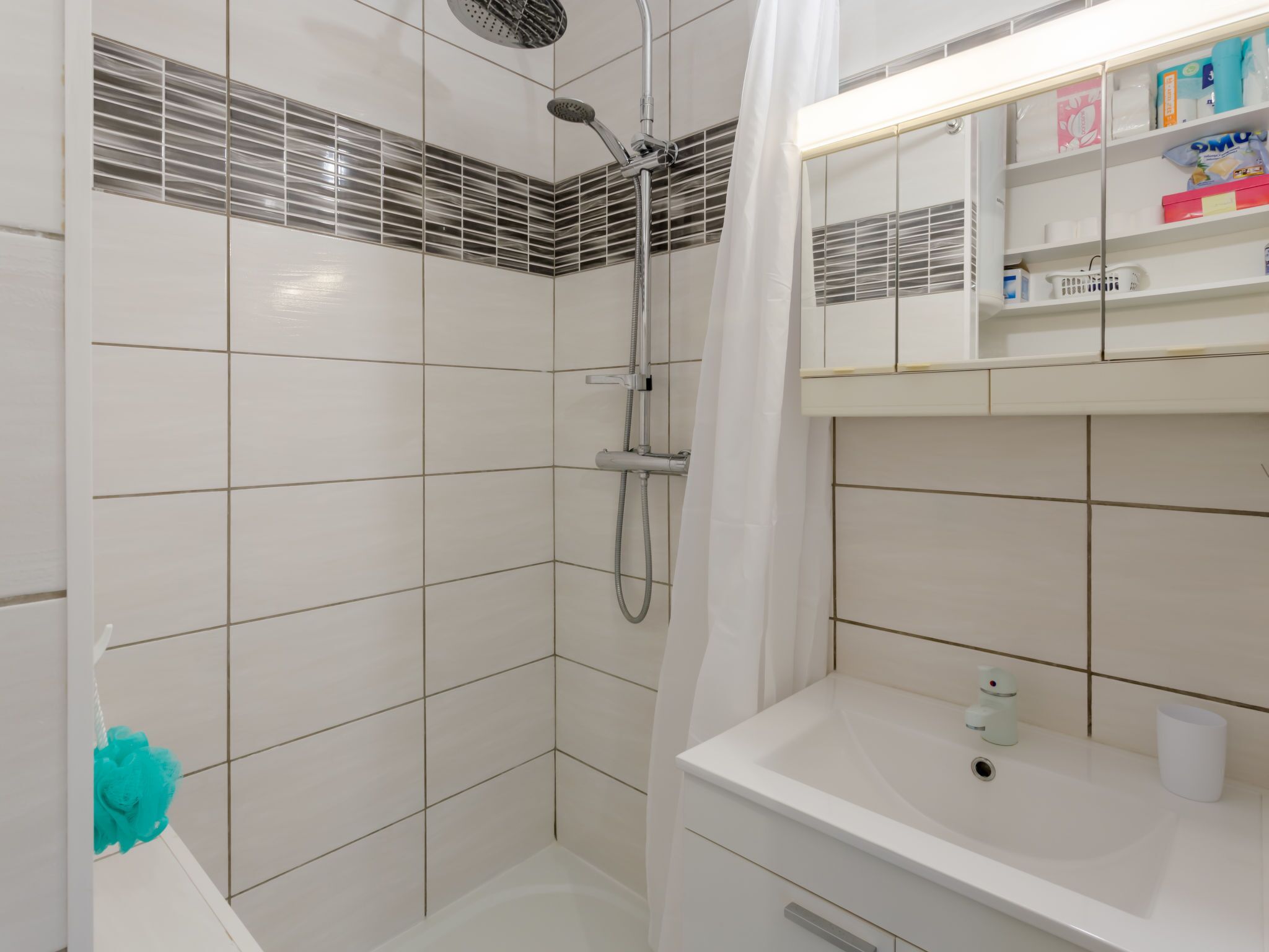A modern bathroom with a shower, a sink, and a mirror.