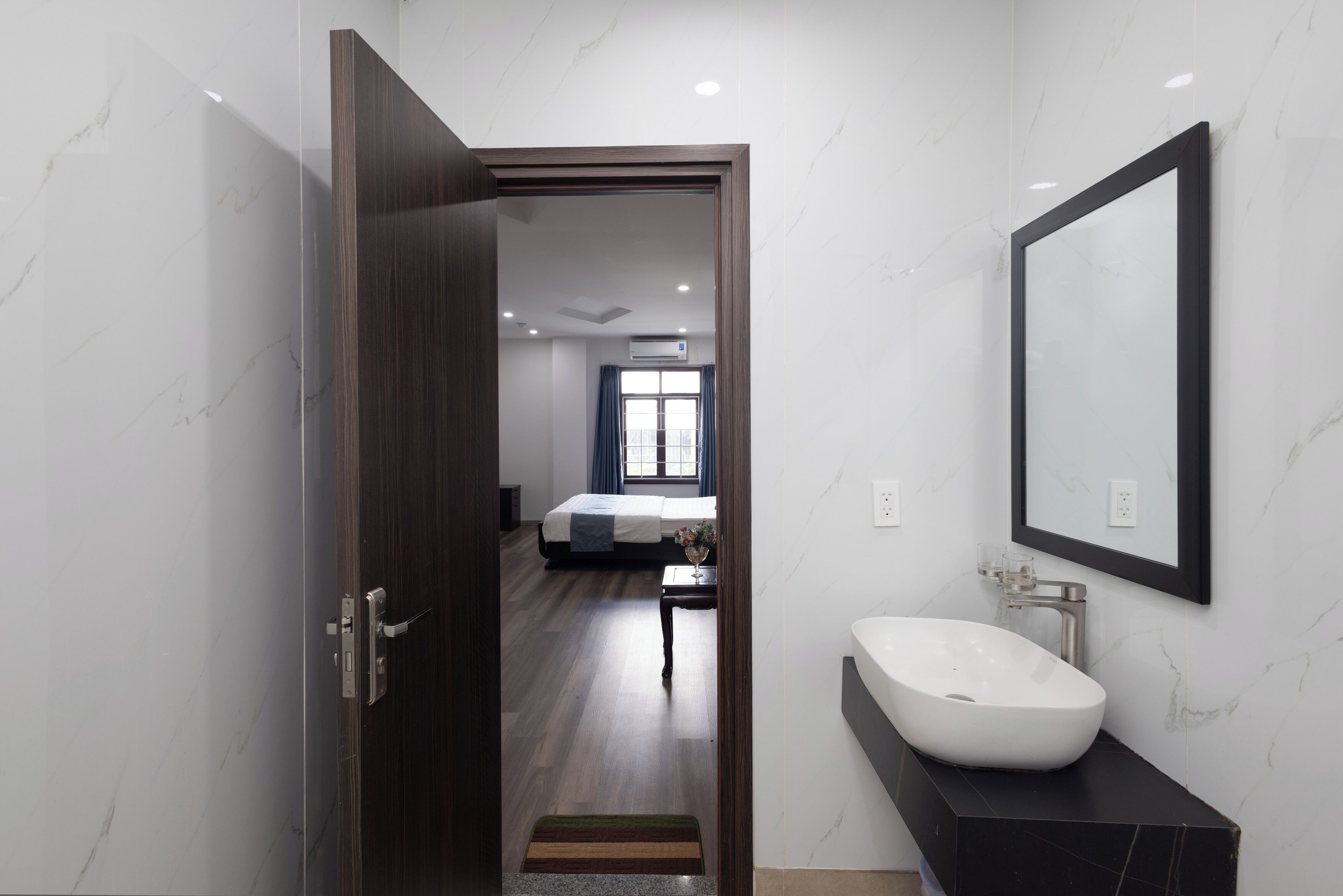 A modern hotel room with a marble bathroom, a large bed, and a view of the city.