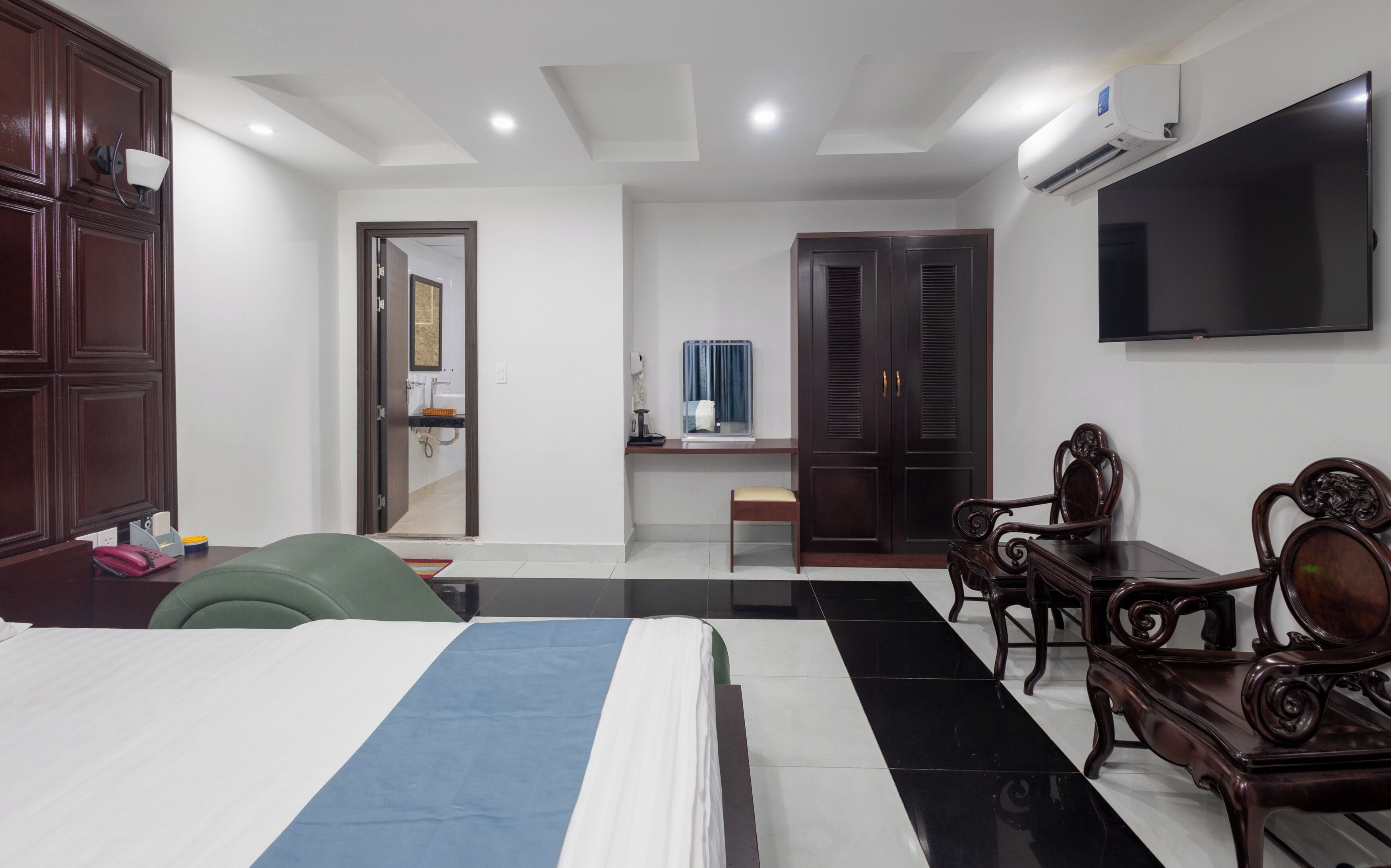 Une chambre d’hôtel comprenant un lit, un bureau avec une chaise, une télévision et une armoire.