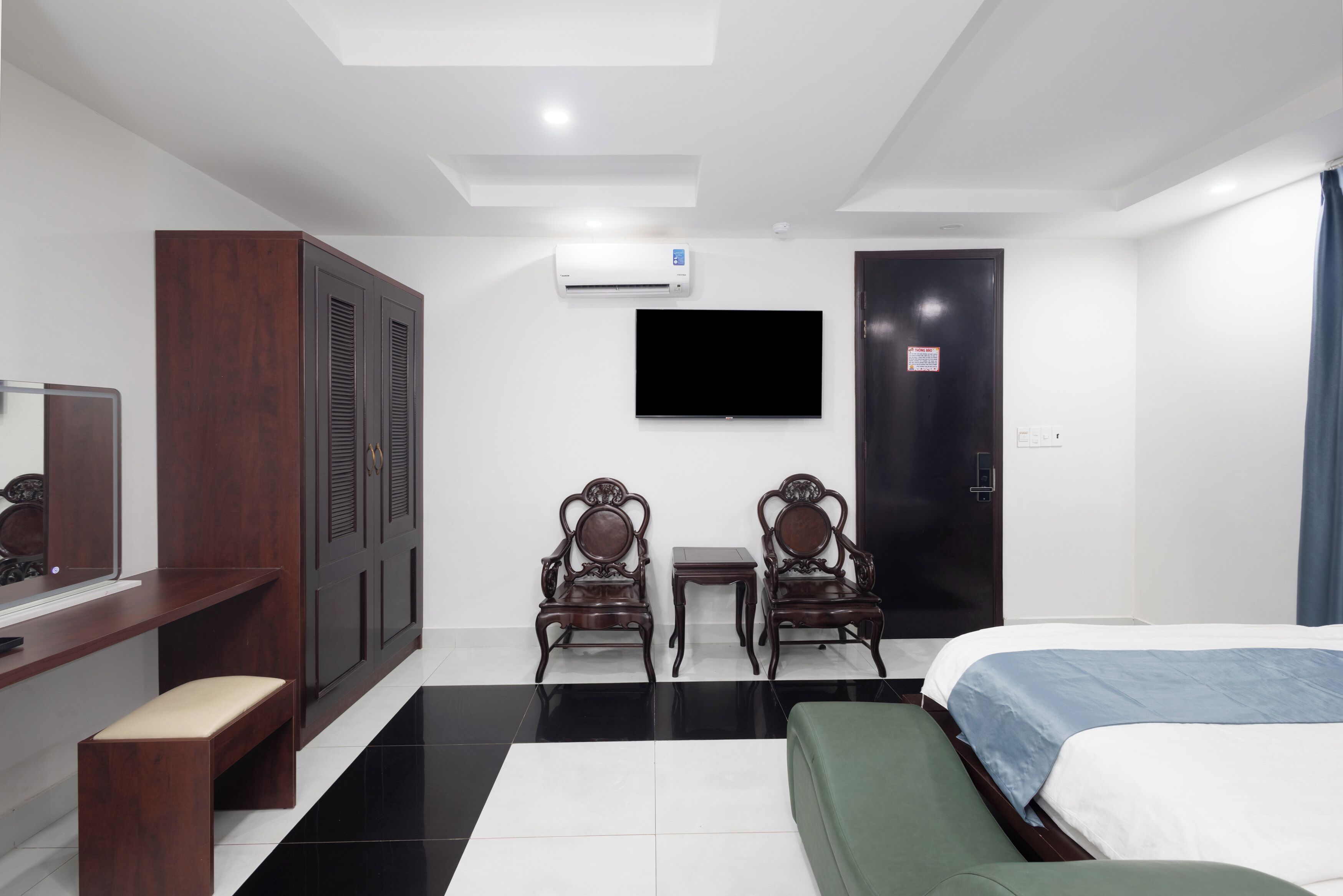 A hotel room with a bed, a desk with a chair, a TV, and a wardrobe.