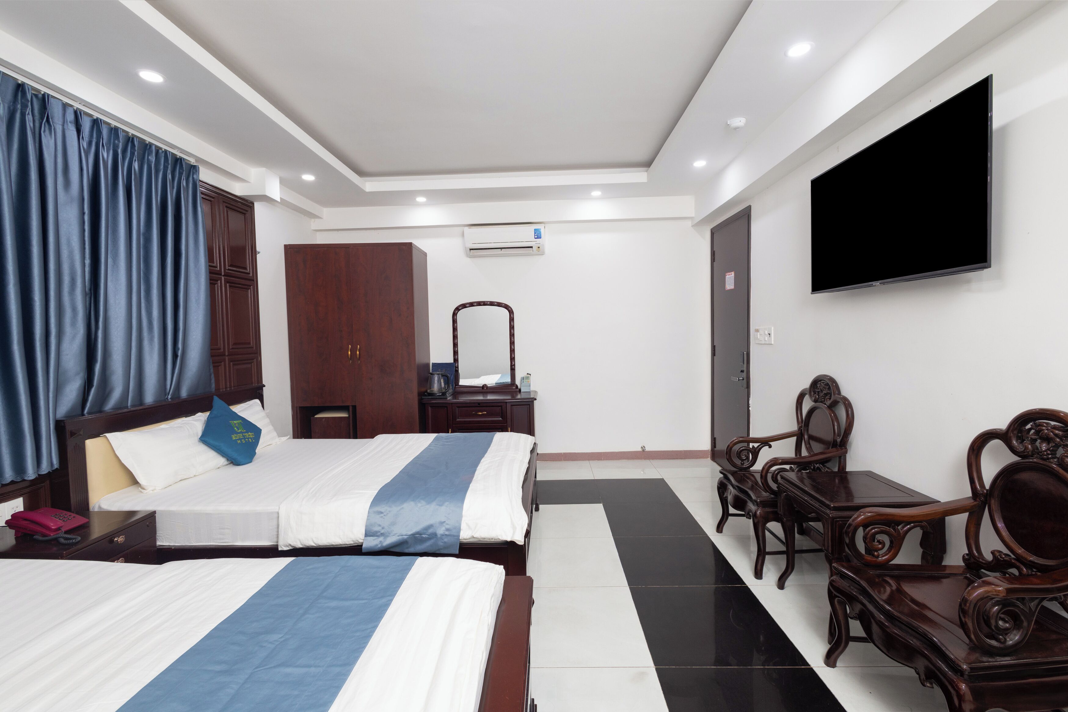 A hotel room with two beds, a TV, a desk, and a wardrobe.