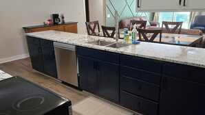Una cocina moderna con armarios oscuros, encimera de granito y lavavajillas empotrado.