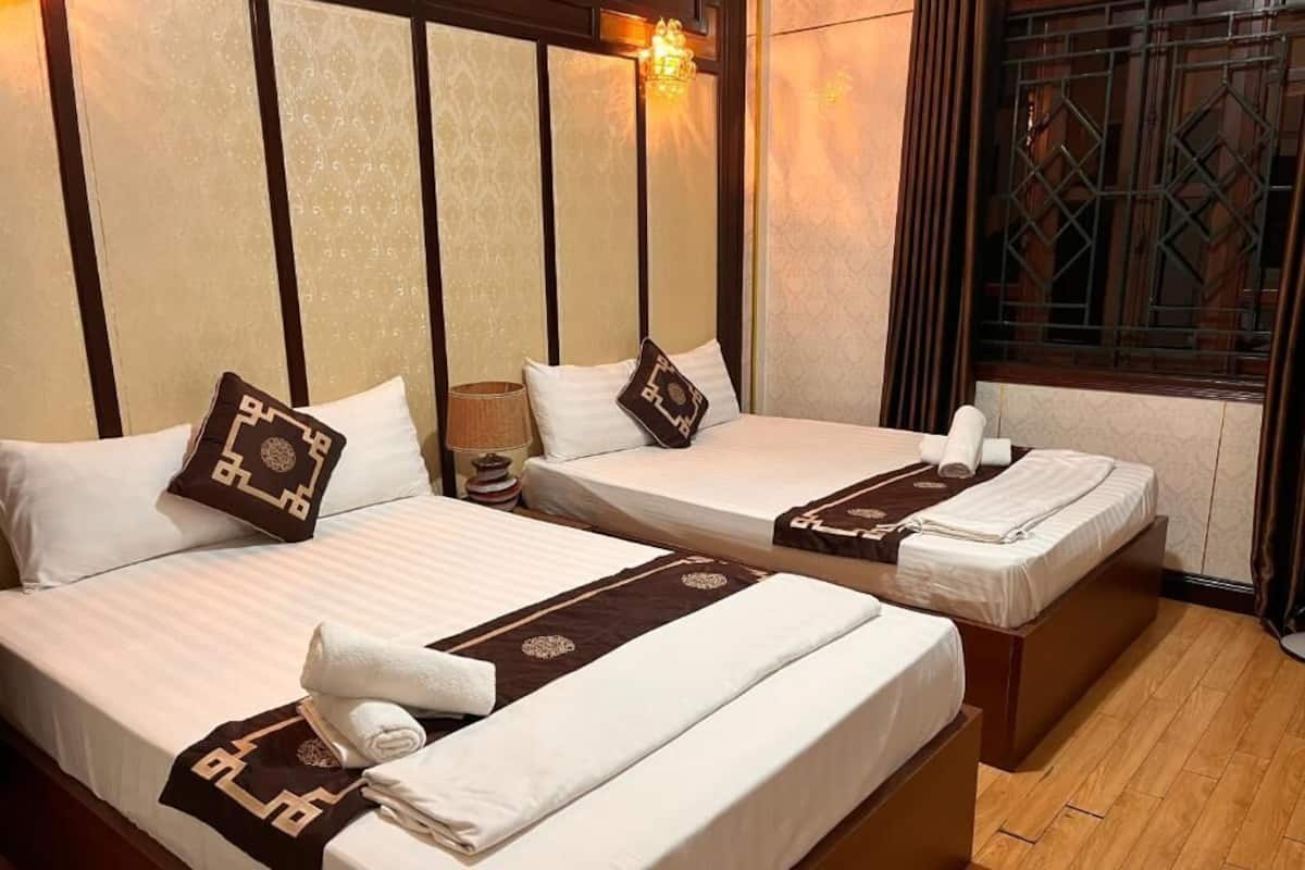 Two single beds with white linens, brown decorative pillows, and a brown headboard.
