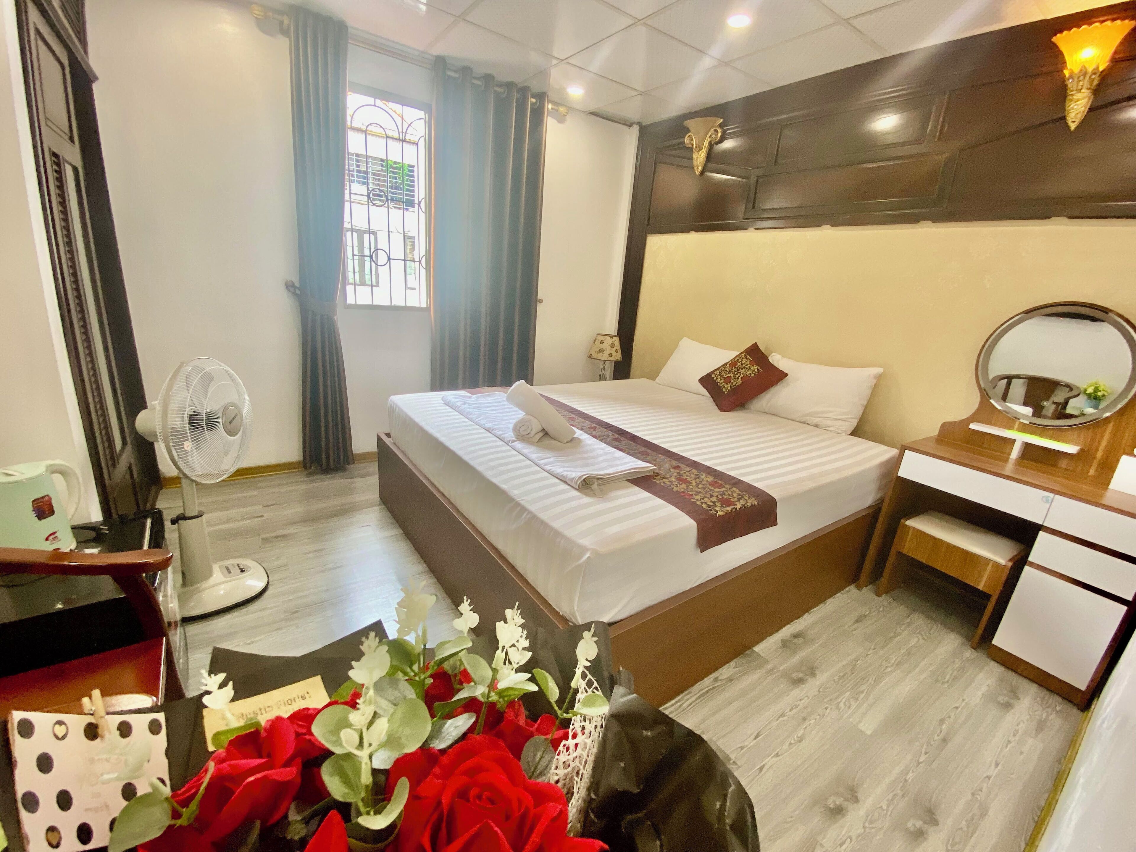 A hotel room with a bed, bedside table, mirror, and a window with curtains.