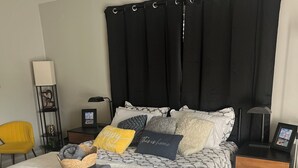 Ein ordentlich eingerichtetes Schlafzimmer mit einem Bett, Nachttischen, einer Lampe und einem Sessel.