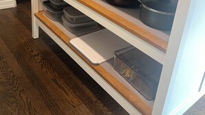 Eine Küche mit Holzböden, die Töpfe und Pfannen beherbergt, einer Ananas-Dekoration und einem an der Wand montierten Fernseher.