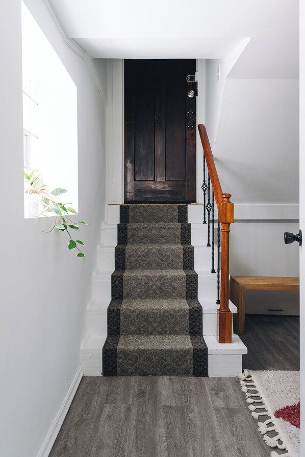 A staircase with patterned carpet, wooden handrail, and a dark door at the top.