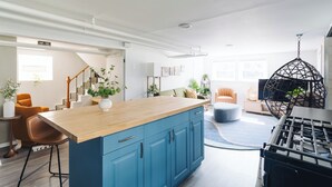 A modern kitchen with blue cabinets, a wooden countertop, and a hanging light fixture. - Sacramento - Stylish 2BR Apt in Irving Park (Chicago)