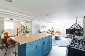 A modern kitchen with blue cabinets, a wooden countertop, and a hanging light fixture. - Sacramento - Stylish 2BR Apt in Irving Park (Chicago)