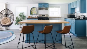 A modern kitchen with blue cabinets, a wooden island, and a hanging chair. - Sacramento - Stylish 2BR Apt in Irving Park (Chicago)