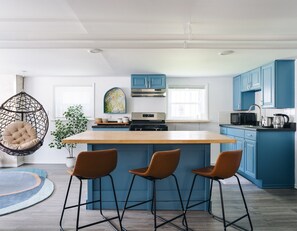 A modern kitchen with blue cabinets, a wooden island, and a hanging chair. - Sacramento - Stylish 2BR Apt in Irving Park (Chicago)