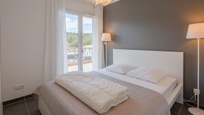 Un dormitorio moderno con una cama grande, vistas al balcón y una lámpara de techo original.