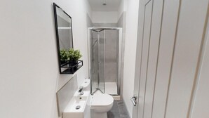 Uma casa de banho moderna com sanita, lavatório e chuveiro.
