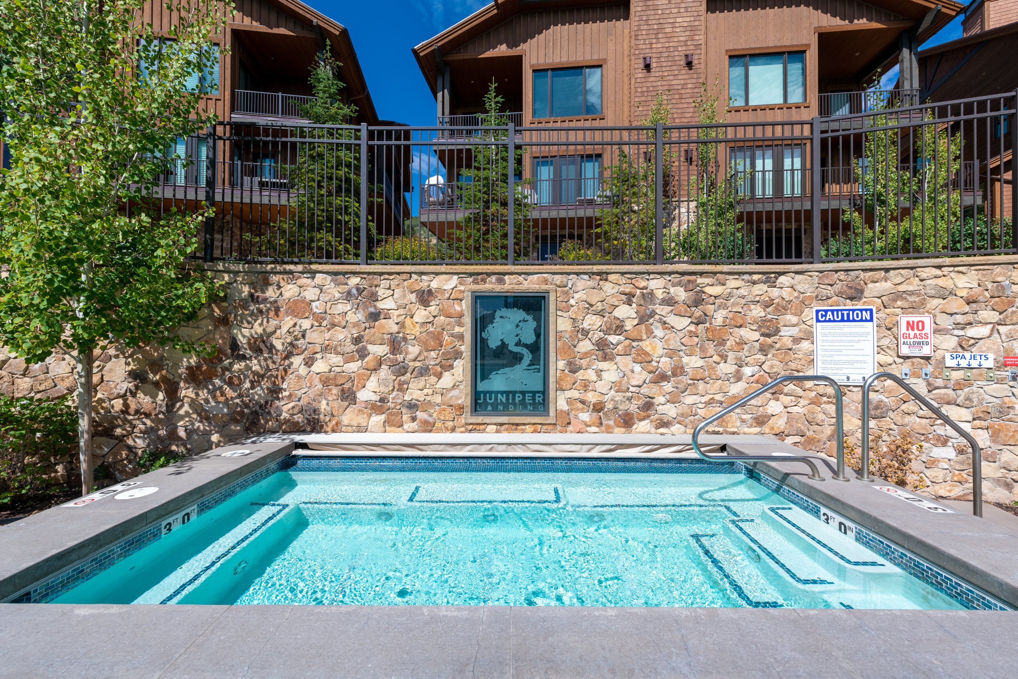 A swimming pool with a stone wall and a Juniper Landing sign.