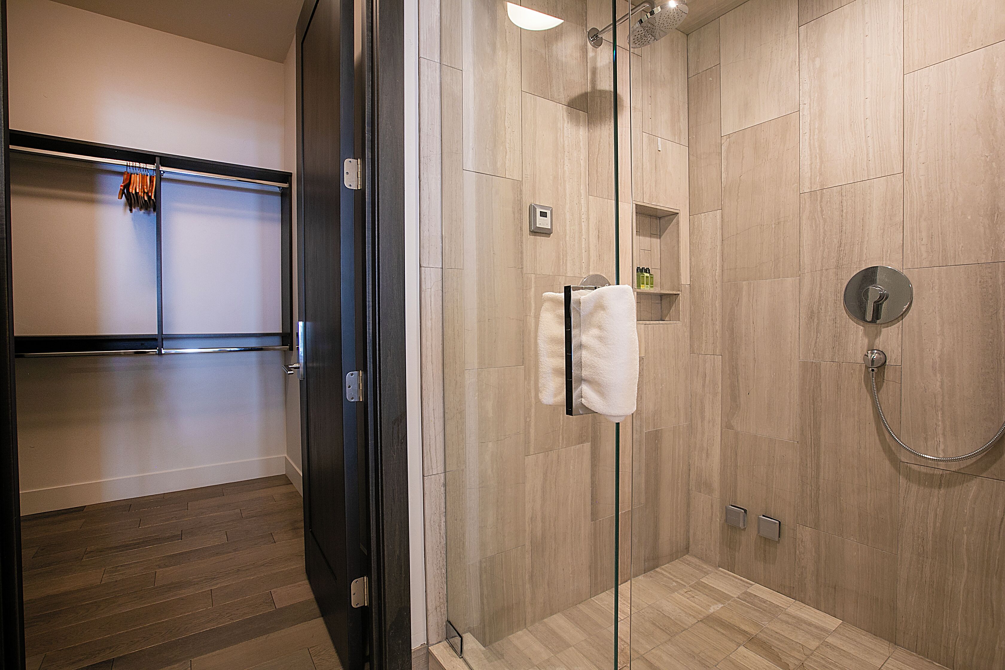 Une salle de bain moderne avec une douche à parois de verre, un plancher en bois et un porte-serviettes.