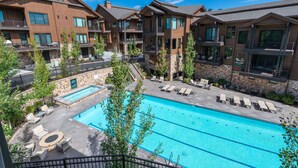 A modern hotel with a swimming pool, outdoor seating, and stone walls. - Walk to Skiing, Exceptional Juniper Landing 5 BR, Private Hot Tub, Golf Course Views, Outdoor Pool (Park City)
