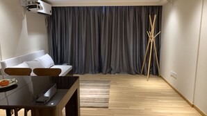 Ein modernes Wohnzimmer mit einer Couch, einem Esstisch und einem an der Wand montierten Projektor.