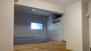 Ein Schlafzimmer mit Bett, Fenster, Kleiderschrank und Deckenleuchte.