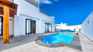 A modern pool area with a clear blue pool, white walls, and a tiled floor.